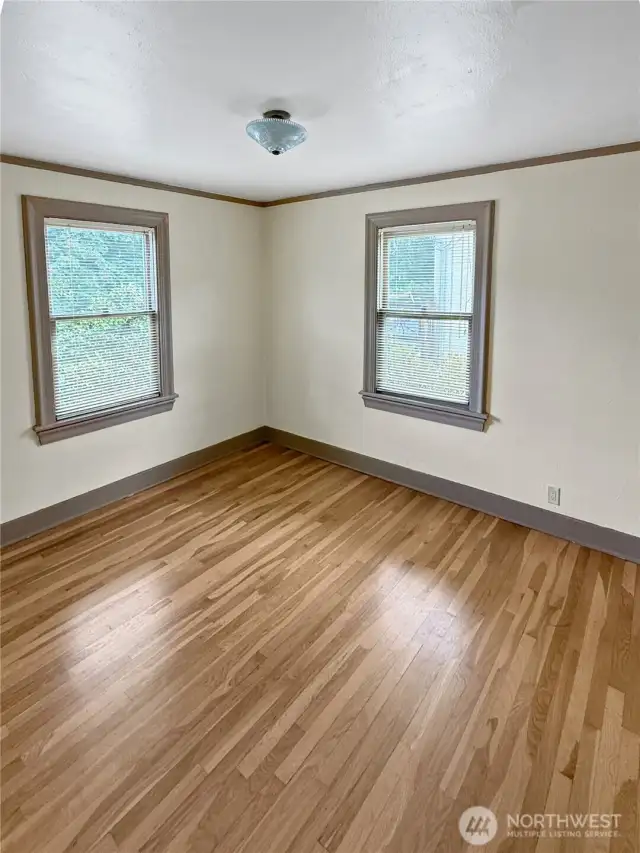 Bright, open, and full of potential — this secondary bedroom is a blank canvas for your vision. Original hardwood floors and vintage window trim keep the home’s 1920s charm intact, while dual windows invite natural light throughout the day. Whether you need a guest room, office, or creative space, this room is ready to make it yours.