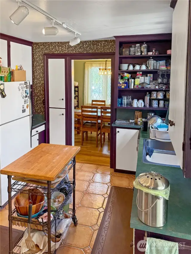 With its bold built-ins, patterned tile floors, and direct access to the dining room, this kitchen radiates personality. Open shelving and a functional layout make it easy to keep essentials within reach, while classic details like wood trim and wallpaper add to the home’s historic appeal. Embrace the original vibe or make it your own — either way, this kitchen is the heart of the home.