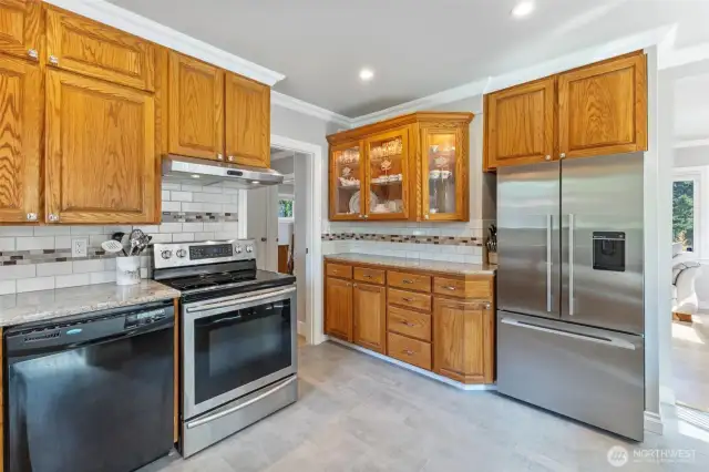 Attractively updated kitchen with tile floors, quartz counters, stainless steel & black appliances, hidden cutting board & knife drawer, & display cabinets.