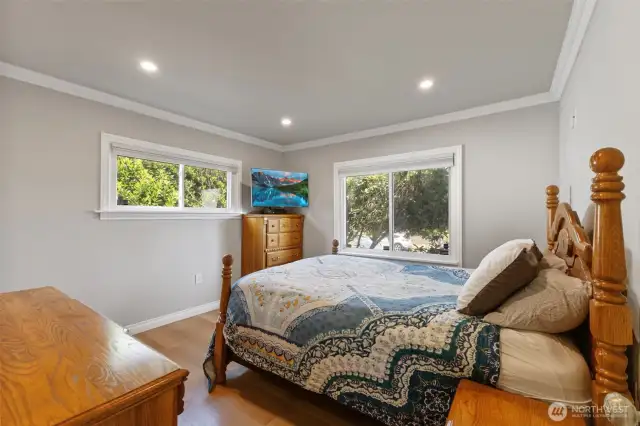 Main floor primary bedroom is light and bright with continued hardwood floors and crown molding.