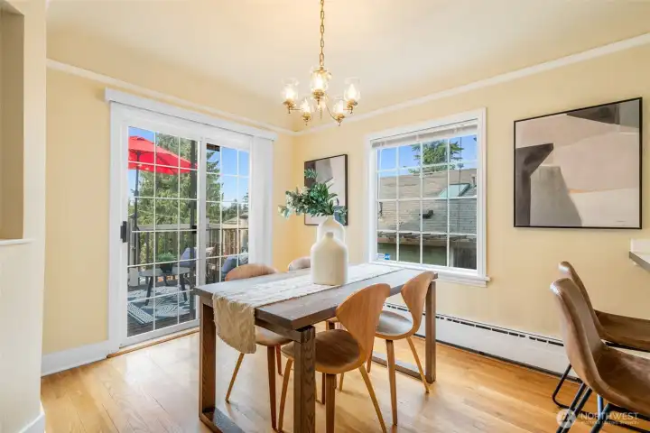 Dining room with sliders to a west-facing front deck and adjoining to a breakfast bar and kitchen.