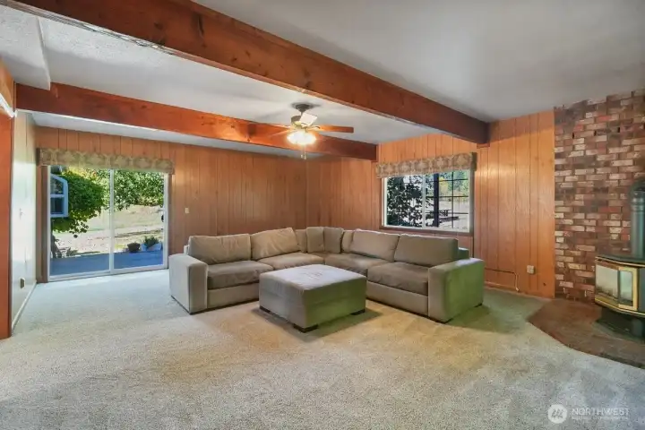 2nd living room with big wood beams, propane stove and back deck.