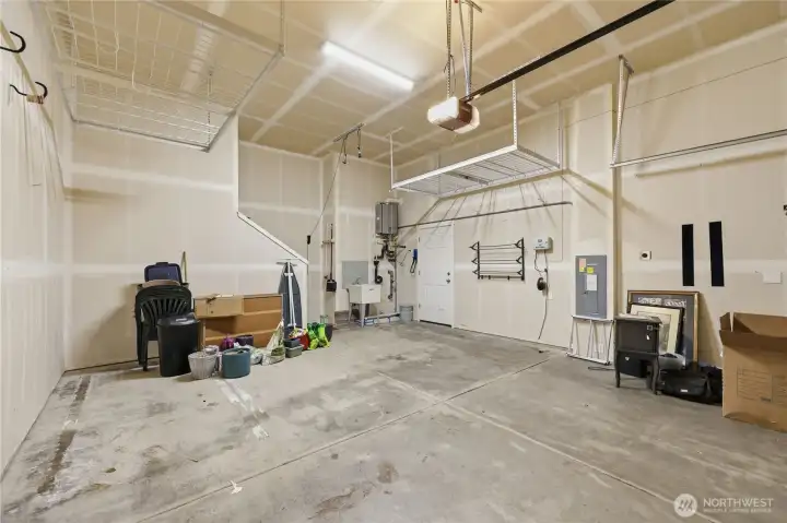 The oversized two-car garage is tall and spacious, featuring built-in overhead shelving, a utility sink, convenient access to the side yard, and a tankless water heater for added efficiency. The oversized two-car garage is tall and spacious, featuring built-in overhead shelving, a utility sink, convenient access to the side yard, and a tankless water heater for added efficiency.