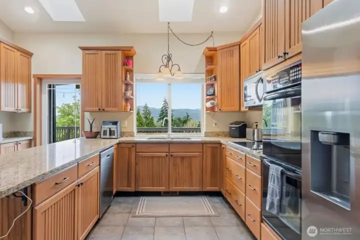 Britgh kitchen with skylights, a large window and walk in pantry
