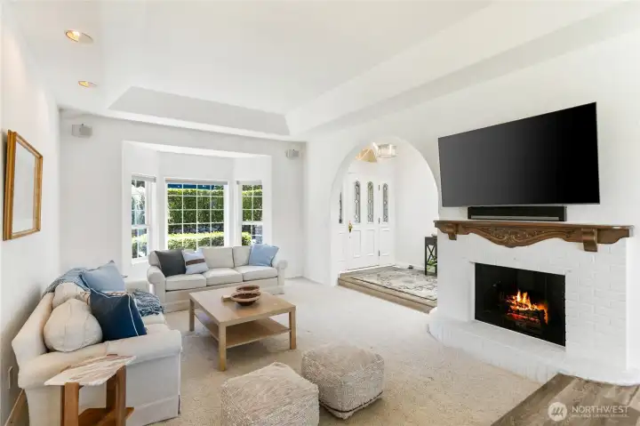 View of the living room from the dining room fireplace and bay windows make this such a comfortable living area