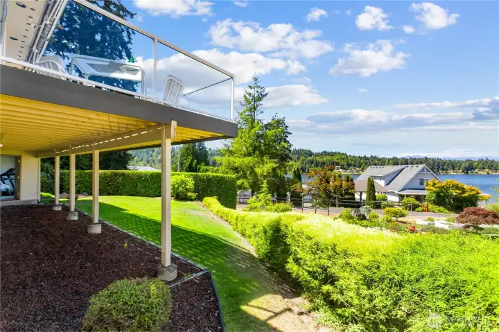 Deck and front yard with hedge between neighbors and your easy care lawn.