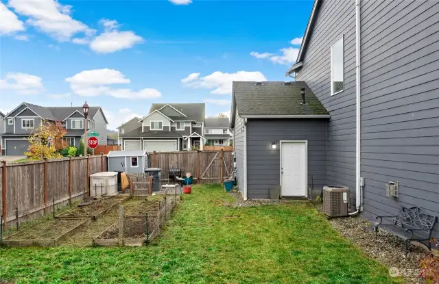 East side of backyard; gate to driveway, more garden space, door to garage.