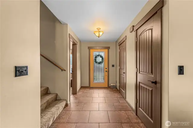 Welcoming entryway with tile floors, wood doors, and natural light.