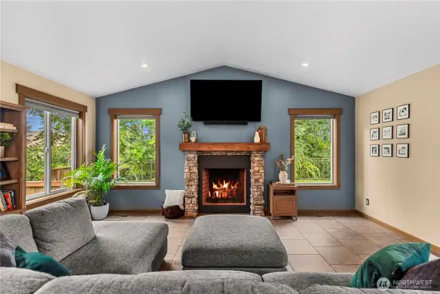 Cozy living room with stone fireplace, large windows, and backyard access.