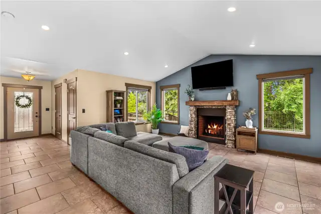Bright living room with stone fireplace, large windows, and serene views.