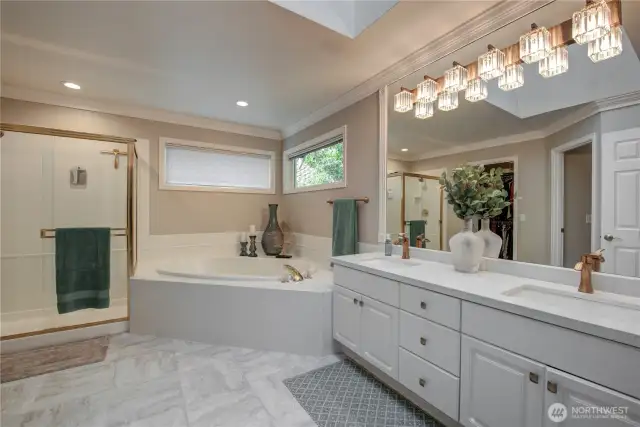 Primary bathroom with a skylight, quartz counter top, crown molding & tile flooring.