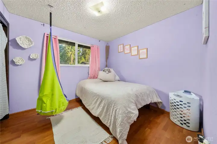 Bright upstairs bedroom featuring a large window for natural light and laminate flooring for easy maintenance. The space offers flexibility for a child’s room, guest space, or home office — one of three upper-level bedrooms providing comfortable separation between living and sleeping areas.