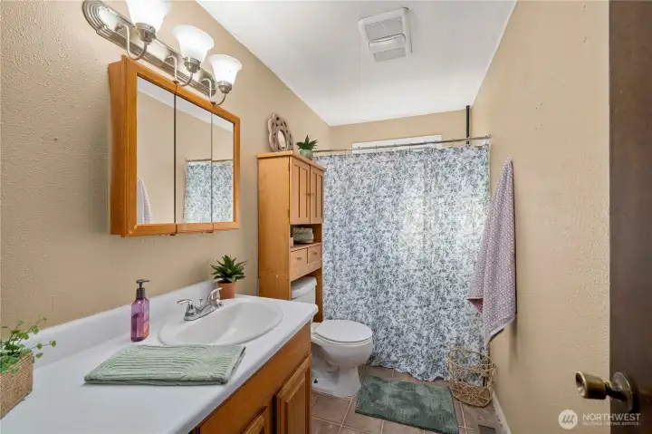 The upstairs full bathroom features a clean and functional layout with a full-sized tub and shower combination, extended vanity for added counter space, and neutral finishes throughout. Conveniently located near all three bedrooms, it serves the upper level with ease—ideal for families or guests sharing the space.