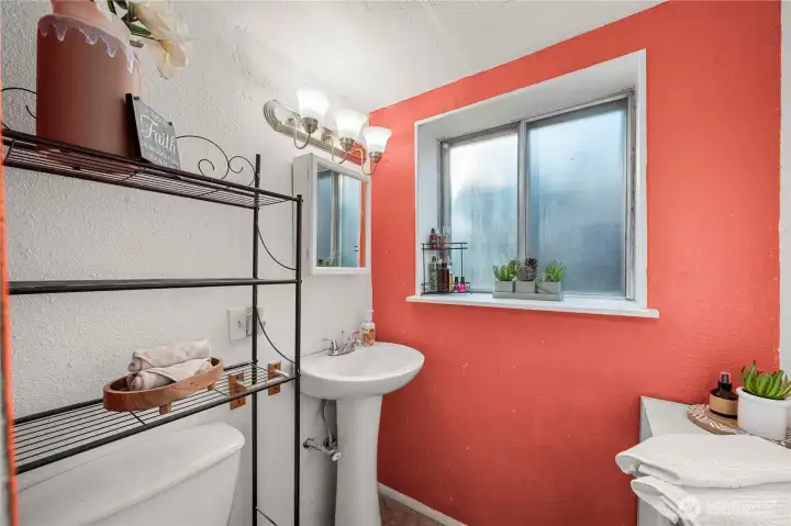 Bright and efficient bathroom space includes a pedestal sink, updated lighting, and a large window that adds natural light—perfect for guests or extended-stay family members using the lower level.