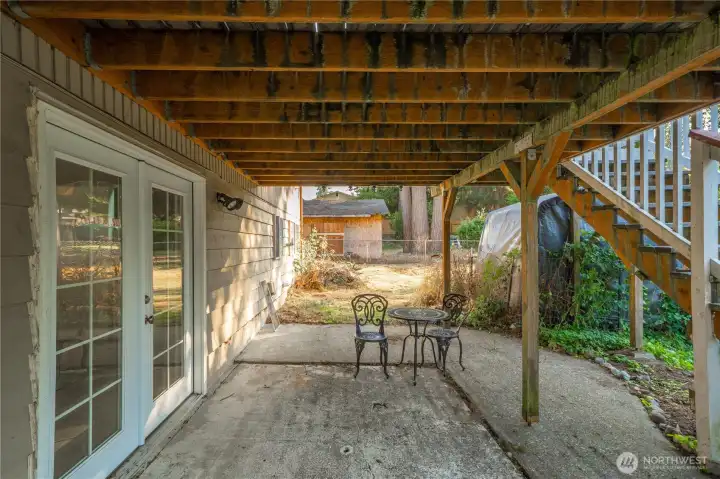 Covered patio beneath the deck provides a shaded retreat ideal for relaxing or entertaining. The lower-level French doors offer convenient private access to the finished basement — perfect for guests, hobbies, or multi-generational living.