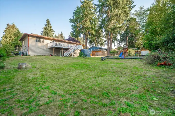 Spacious, gently sloped backyard surrounded by mature evergreens, offering privacy and plenty of room to roam. The elevated deck and daylight basement design make full use of the lot’s natural grade while adding visual interest and outdoor functionality.