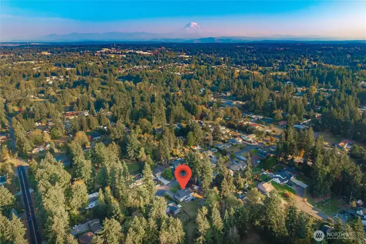Breathtaking aerial view captures the home’s peaceful neighborhood setting surrounded by evergreens, with a clear view of Mount Rainier in the distance — a true Pacific Northwest backdrop.
