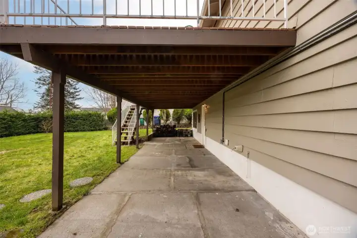 Patio area under the deck; and stairs back to the deck. Lower level entry on the right, at the mat.