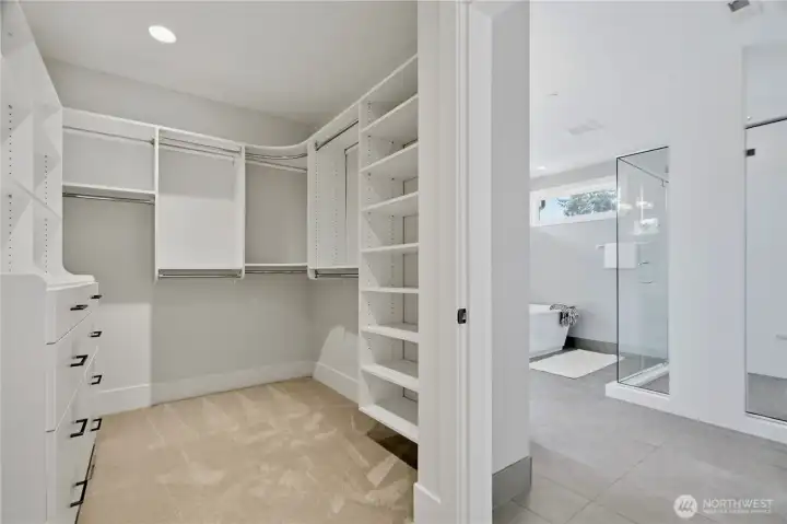 Large walk-in closet with built-in shelving located just off the primary bathroom.