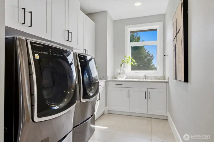 Upstairs laundry room with abundant storage, natural light, and generous counter space for added convenience