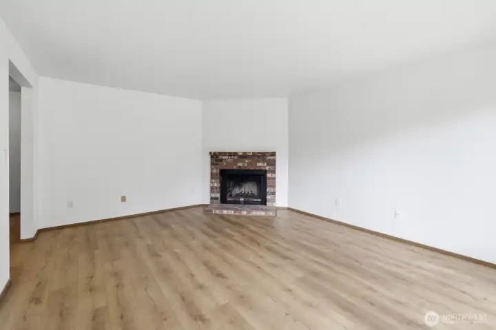 Living area offers new LVP flooring and a wood burning fireplace.