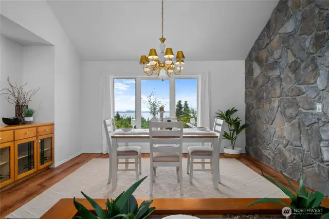 Formal dining area framed by natural stone and expansive windows overlooking Puget Sound and the islands beyond.
