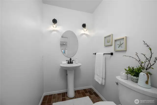 Bright and modern powder room with pedestal sink and stylish lighting—simple, elegant, and welcoming.