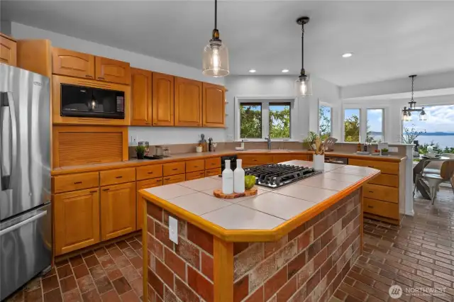 Cook with a view in this gourmet kitchen featuring tile counters, gas island range, and stainless appliances.