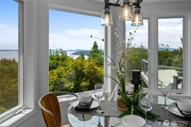 Charming dining nook wrapped in windows—enjoy meals with sweeping views of water, trees, and sky.
