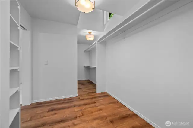 Primary bedroom spacious walk-in closet with custom shelving, stylish light fixtures, and thoughtful architectural touches—bathed in natural light for a bright and beautifully functional space.