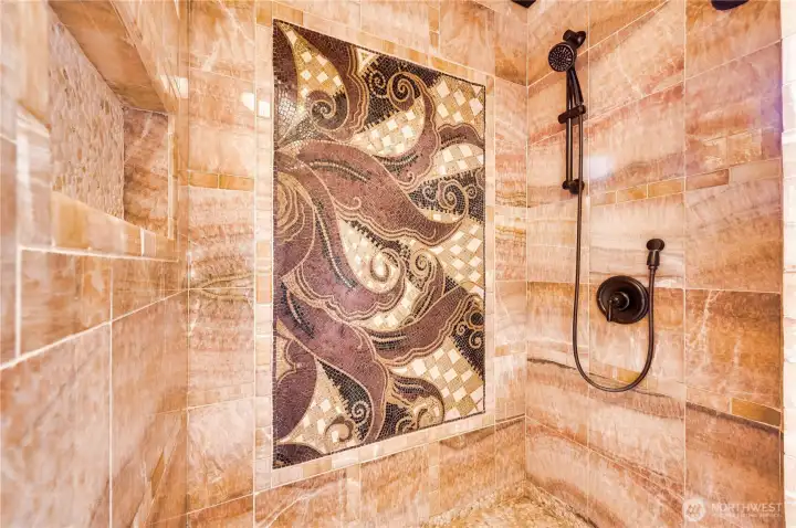 The main floor shower finished in natural Honey Onyx stone and features an imported natural stone mosaic.