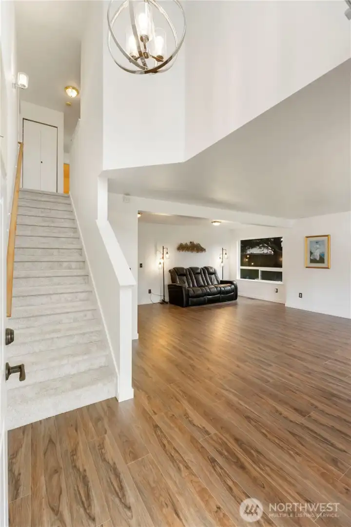 Entry view looking into living dining room with new chandelier and carpeting headed up stairs to 4 large bedrooms