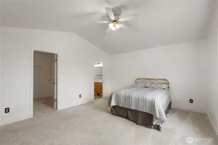 Large primary bedroom view with walk in closet vaulted ceilings and primary bathroom