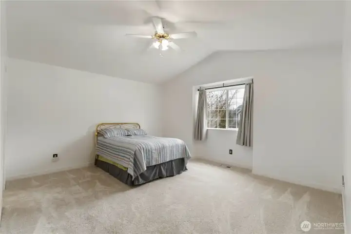 Second view of large primary bedroom with views out front of home and room for all your furniture