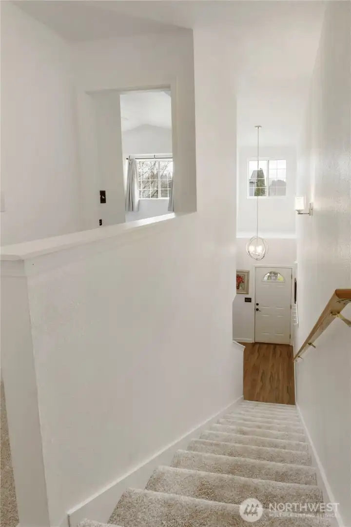 Hall stairs leading to entry way with new paint and carpeting upstairs to keep you warm