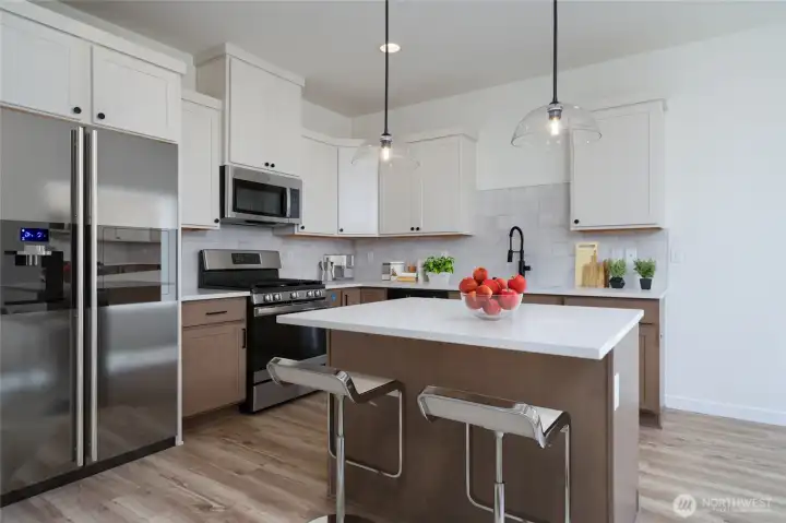Kitchen has an island, fridge, dw, range & quartz countertops.