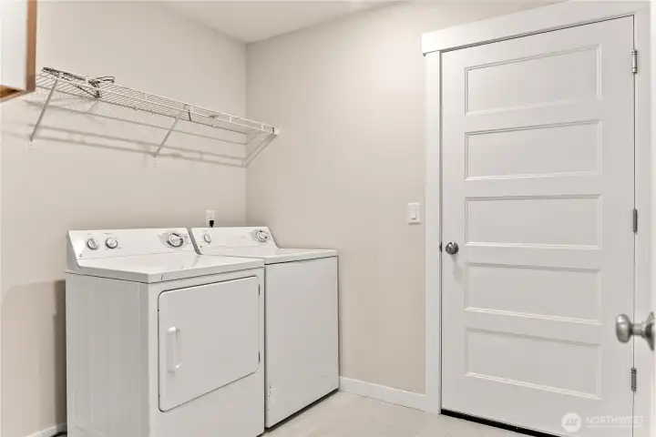 Spacious laundry room with shelving for storage of supplies