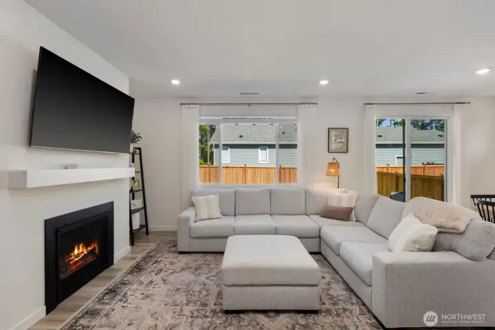 Large windows and an open layout fill the great room with natural light, while the fireplace creates a comfortable focal point for gathering and relaxing.