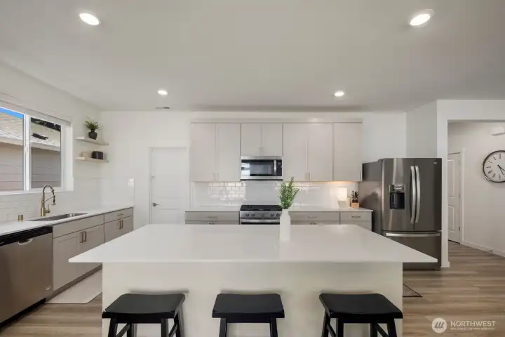 Featuring quartz countertops, upgraded cabinetry, generous prep space, and a large island with seating, the kitchen was designed to support both everyday routines and entertaining.