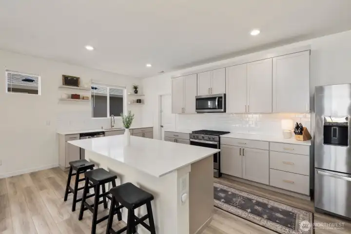 The kitchen combines modern finishes, ample storage, quartz surfaces, and a functional layout that anchors the home's open living spaces.