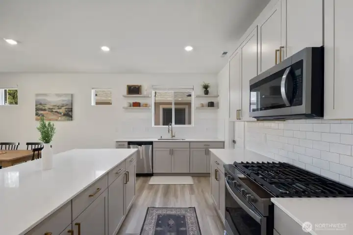 The kitchen offers a functional layout with quartz countertops, upgraded cabinetry, generous storage, and a large island that creates additional workspace and casual seating.
