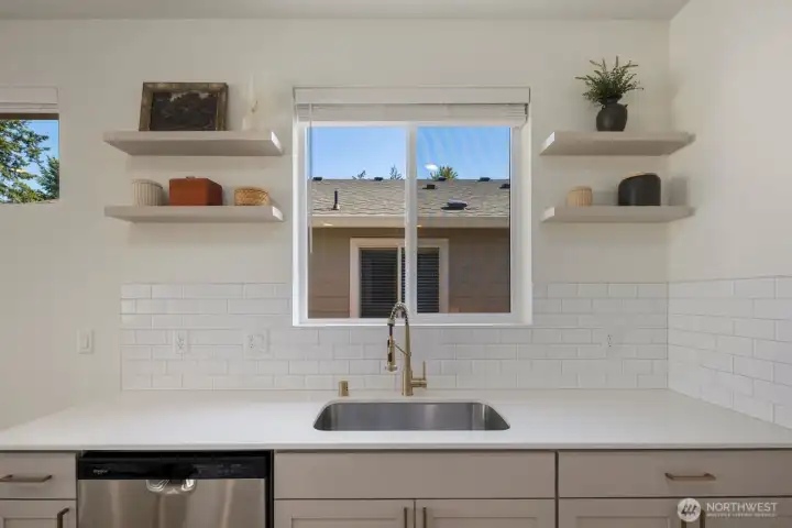 Open shelving, quartz surfaces, and a central sink location add both convenience and style to this thoughtfully designed kitchen.