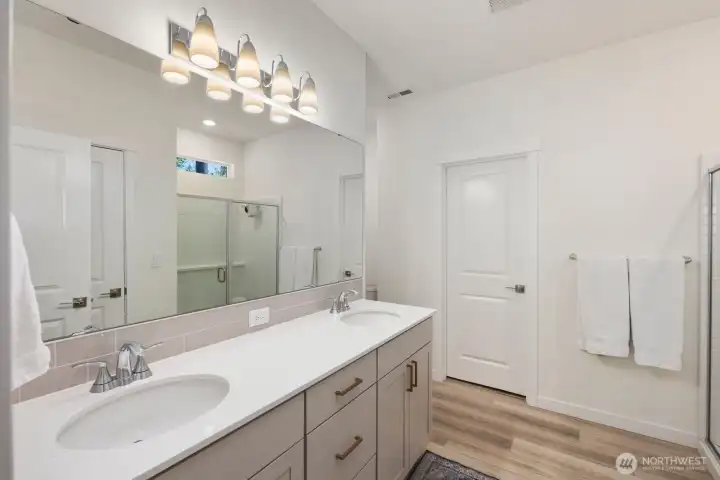 The spacious primary bathroom features a dual-sink vanity, quartz countertops, abundant storage, and a bright, open layout designed to make busy mornings a little easier.