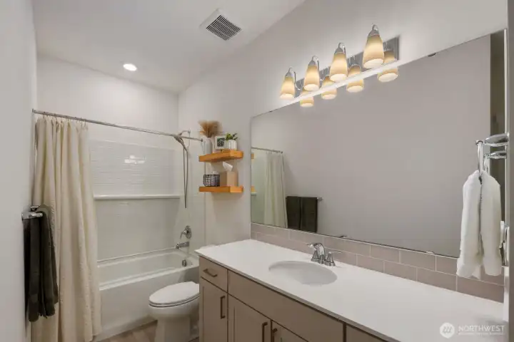 The bathroom features quartz countertops, ample vanity space, and a clean, modern design that complements the home's newer construction.
