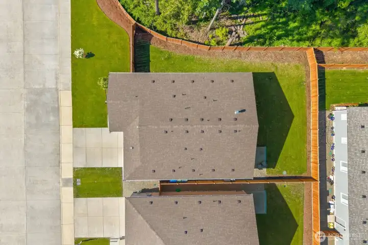 A top-down view highlights the home's generous lot, usable outdoor space, and position along the edge of the neighborhood with trees directly behind the property.