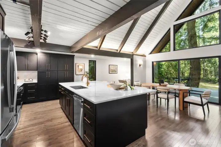 The impeccably designed kitchen is a chef's dream, boasting an abundance of sleek cabinetry, subtle under-cabinet task lighting, and premium matching stainless steel appliances. Expansive white quartz countertops provide endless prep space and wrap into a massive island perfect for casual dining. With fluid transition from the kitchen to the main living area, this light-filled home is an absolute masterpiece for both entertaining and luxurious daily living.