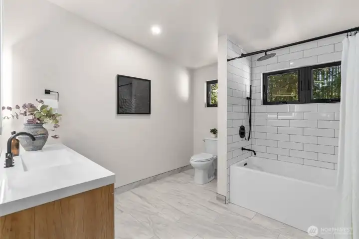 Just steps away, the gorgeous ensuite bathroom serves as your private spa—featuring a beautiful light wood vanity with caned-front accents, modern matte-black hardware, an LED-backlit mirror, and a pristine subway-tiled tub and shower. It’s a masterfully designed space dedicated entirely to rest and rejuvenation.