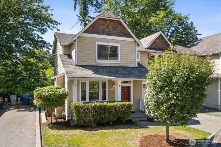 Second exterior angle showcasing the charming roofline and mature trees that add natural privacy.