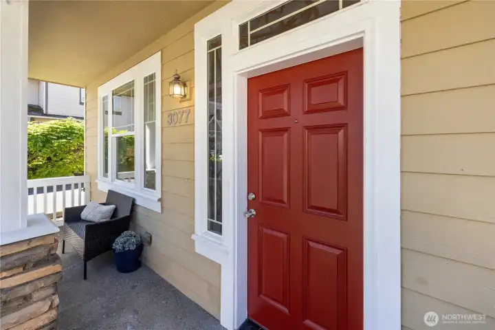 Welcoming covered front porch with that bold red door — a great spot to enjoy a morning coffee.