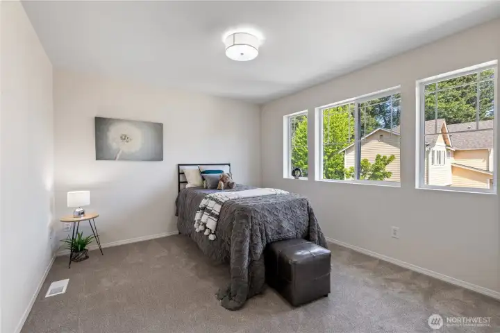 Bright bedroom with large windows that bring in beautiful greenery views.